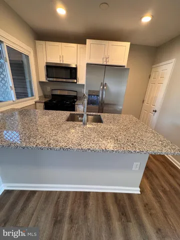 a kitchen with kitchen island granite countertop a stove and a sink