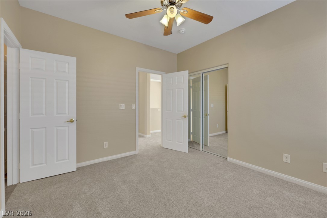10328 Hawk Ravine Street Las Vegas, NV 89178 - Photo 30 of 55 A quiet bedroom retreat with plush carpeting and a modern ceiling fan, offering a serene escape.