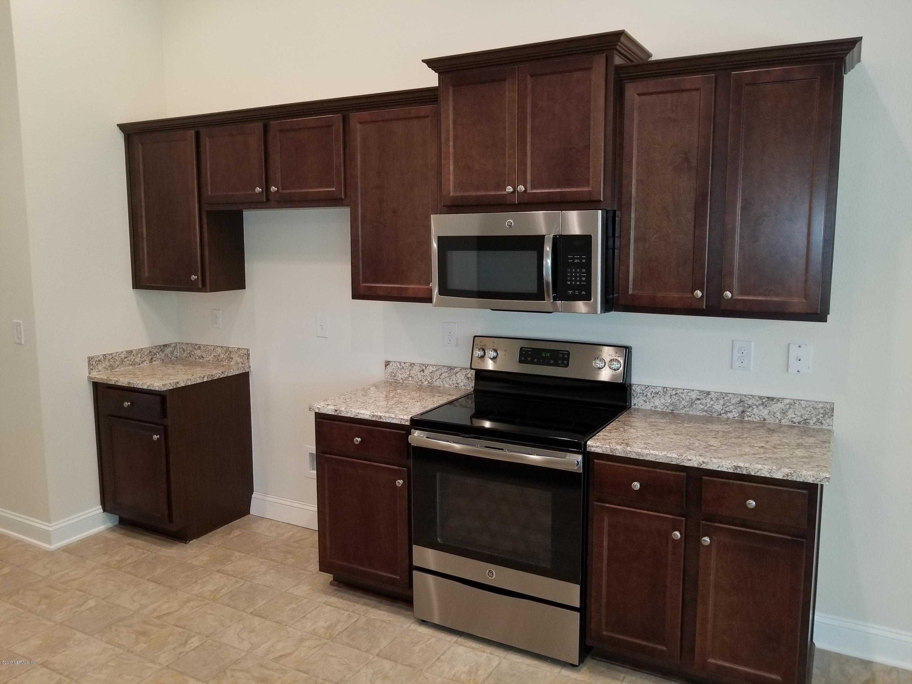 88253 Maybourne Road Yulee, FL 32097 - Photo 10 of 29 a kitchen with granite countertop wooden cabinets and stainless steel appliances