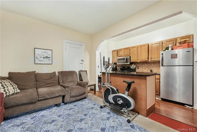 a living room with furniture a flat screen tv and a refrigerator