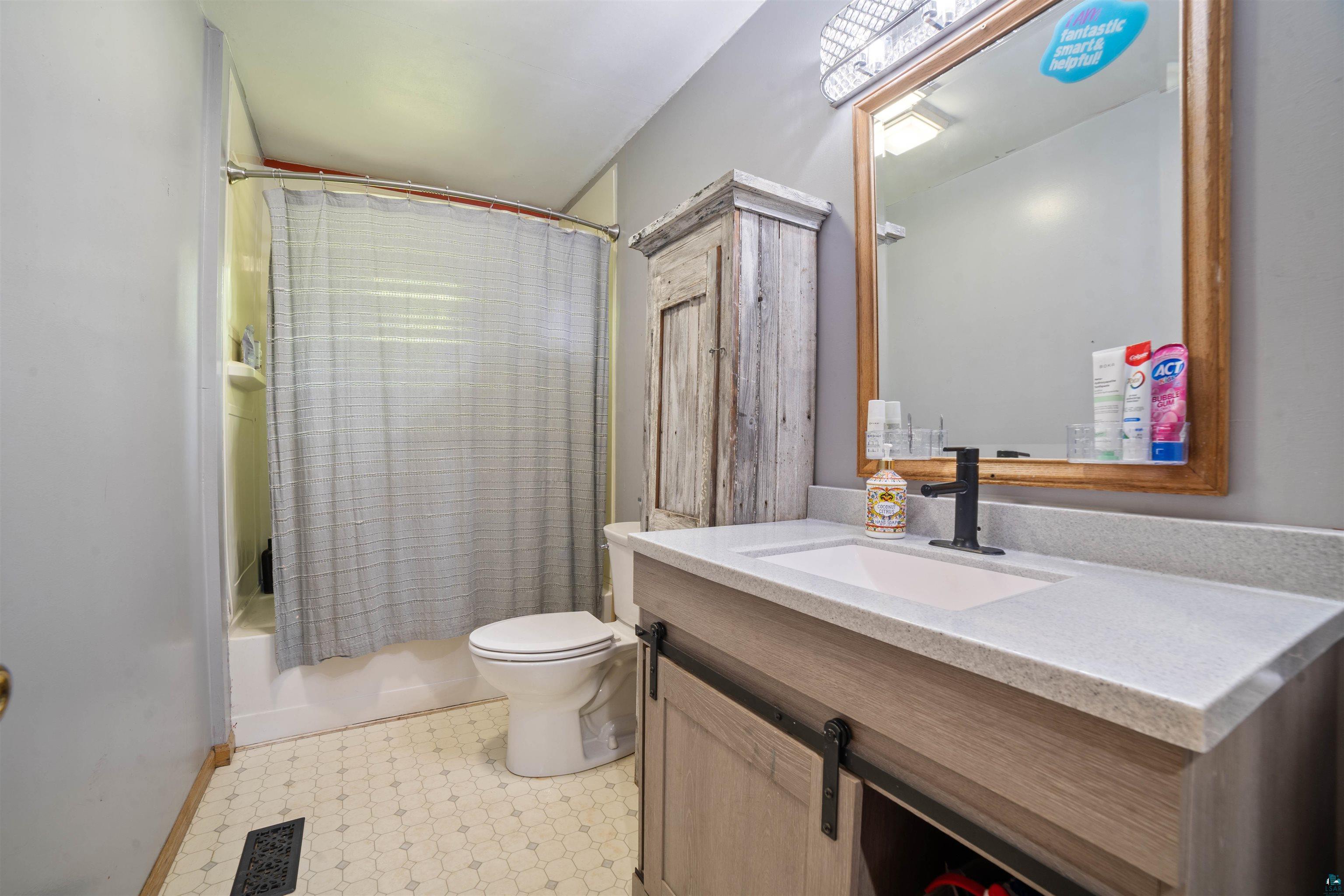9076 East Moonshine Road South Range, WI 54874 - Photo 14 of 26 Full bathroom with tile flooring, oversized vanity, toilet, and shower / bath combination with curtain