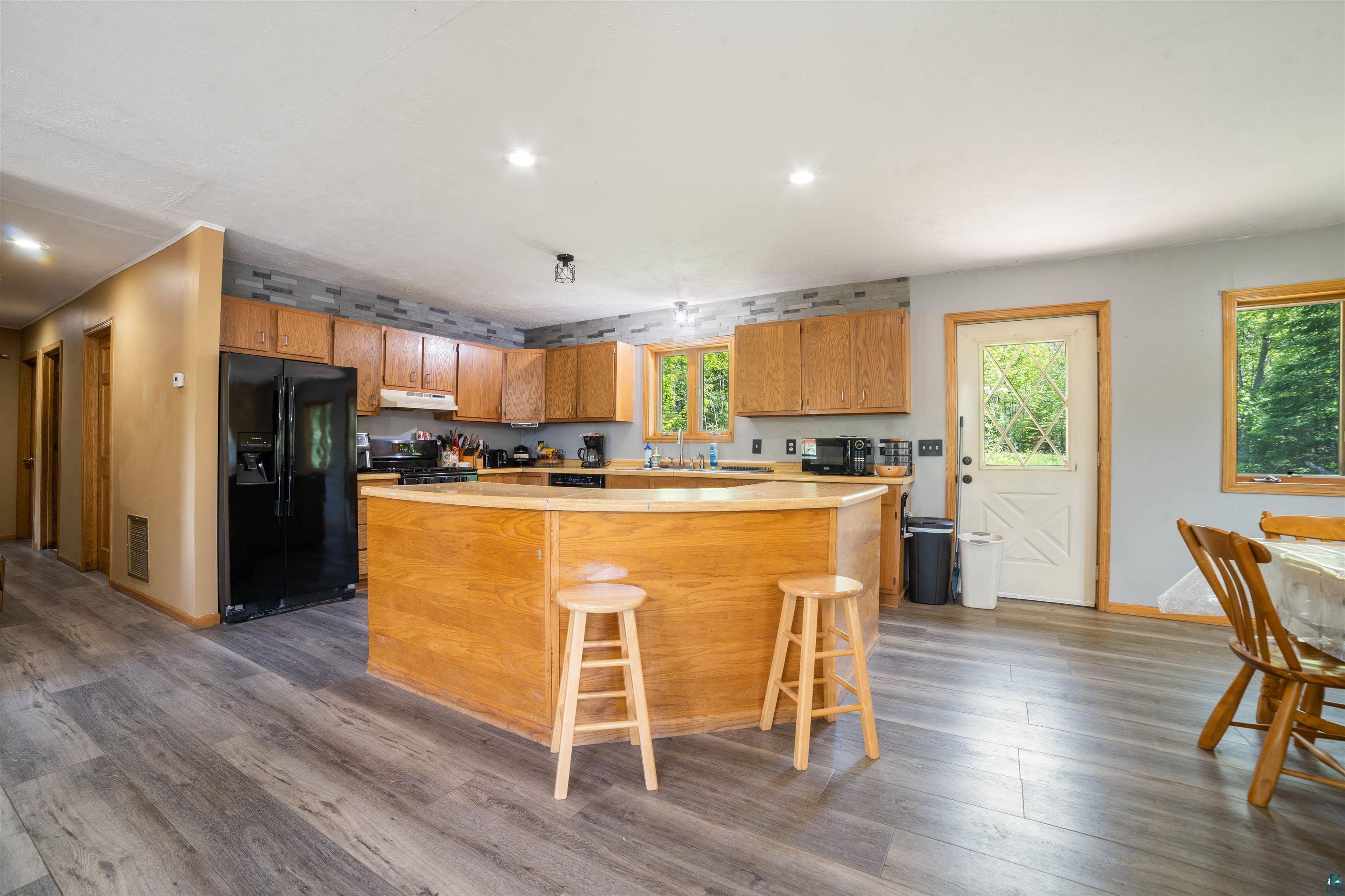 9076 East Moonshine Road South Range, WI 54874 - Photo 10 of 26 Kitchen featuring black fridge, dark hardwood / wood-style flooring, ventilation hood, and a kitchen island