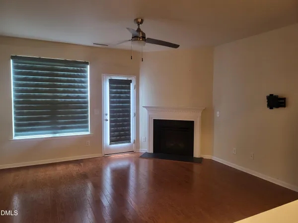a view of a livingroom with a fireplace window and wooden floor