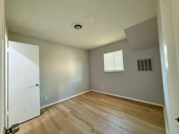 an empty room with wooden floor and windows
