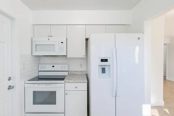 a kitchen with white cabinets and white appliances