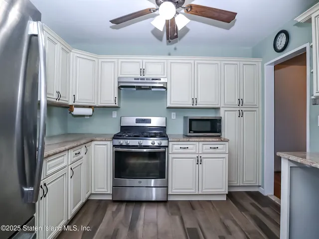 a kitchen with stainless steel appliances a stove a microwave and white cabinets