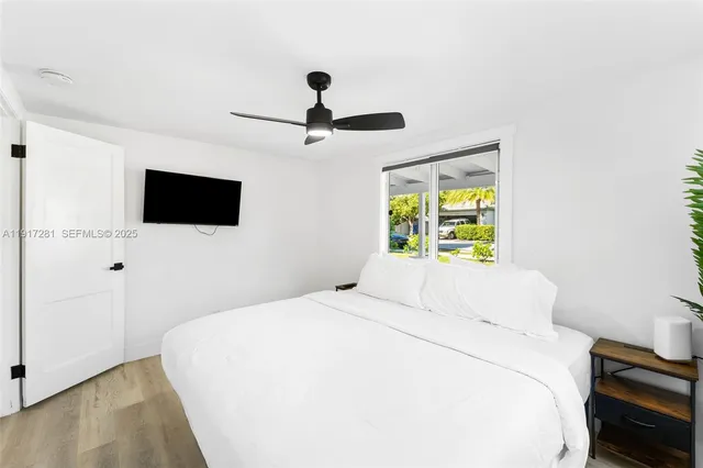 a bedroom with a large bed a flat tv screen and a window