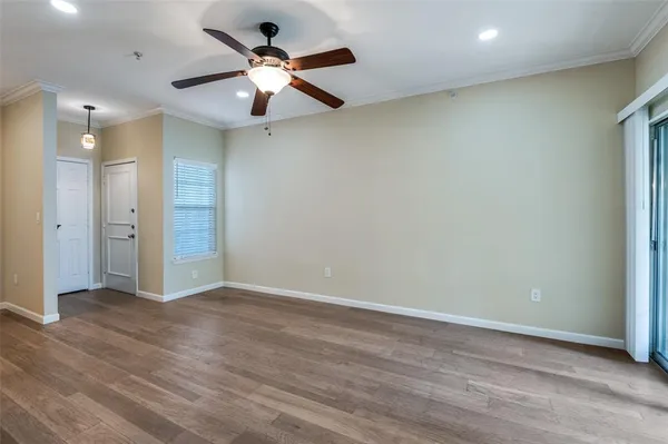 an empty room with wooden floor and a ceiling fan