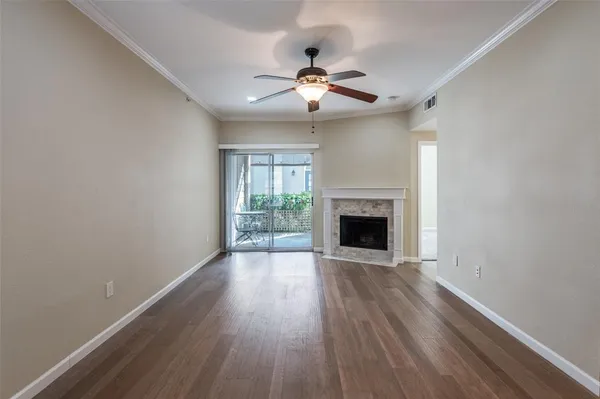 a view of an empty room with wooden floor fireplace and a window