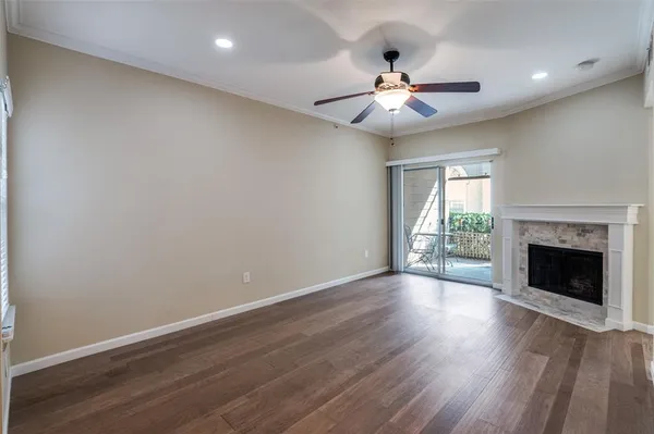 a view of an empty room with wooden floor fireplace and a window