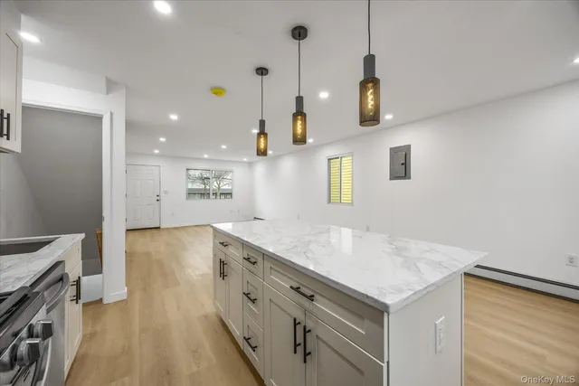 a kitchen with a stove a sink a center island and wooden floor