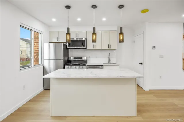 a kitchen with kitchen island a sink a stove a refrigerator and white cabinets