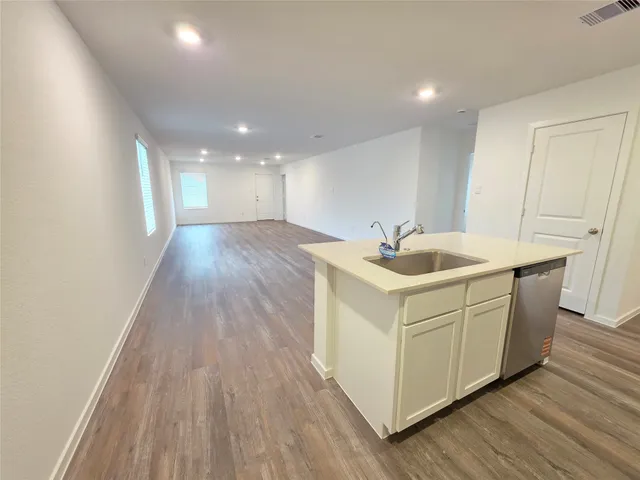 a room with kitchen island a sink wooden floor and a living room view