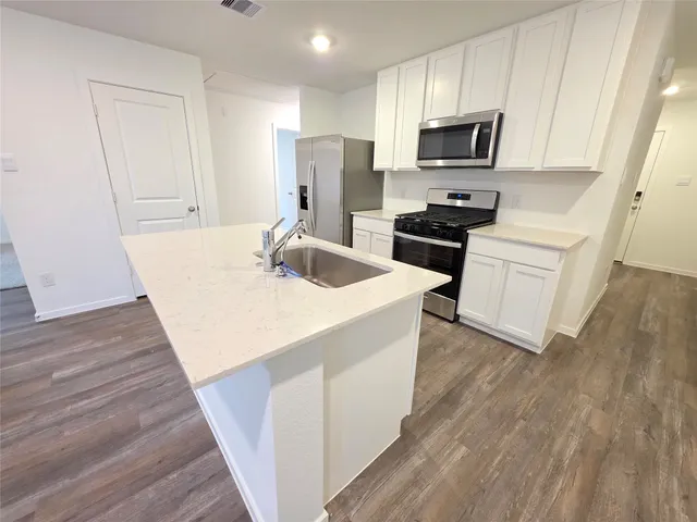 a kitchen with a sink a microwave a refrigerator and cabinets