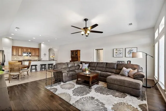a living room with furniture kitchen view and a wooden floor