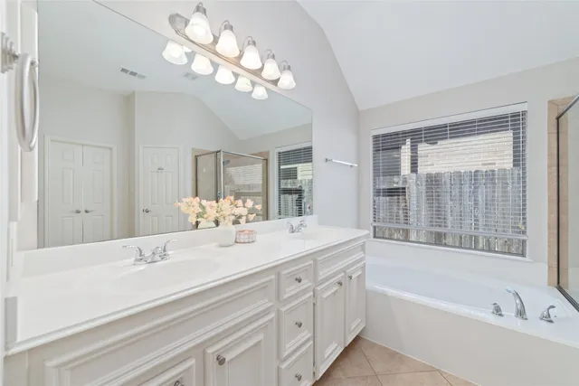 a bathroom with a bathtub a double vanity sink and a mirror
