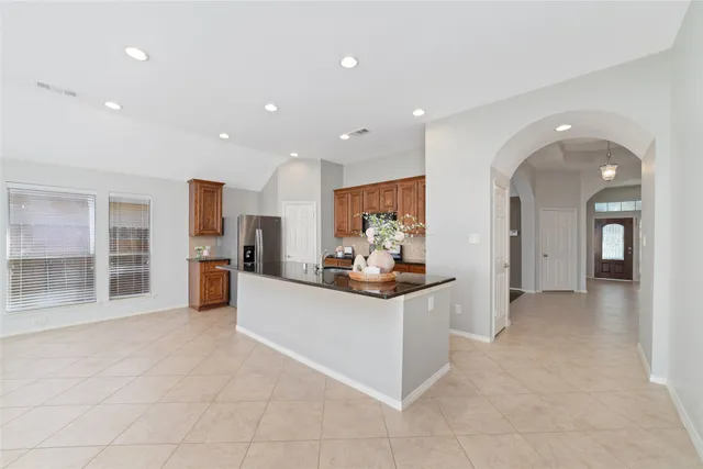 a large white kitchen with stainless steel appliances granite countertop a large counter top and a stove top oven