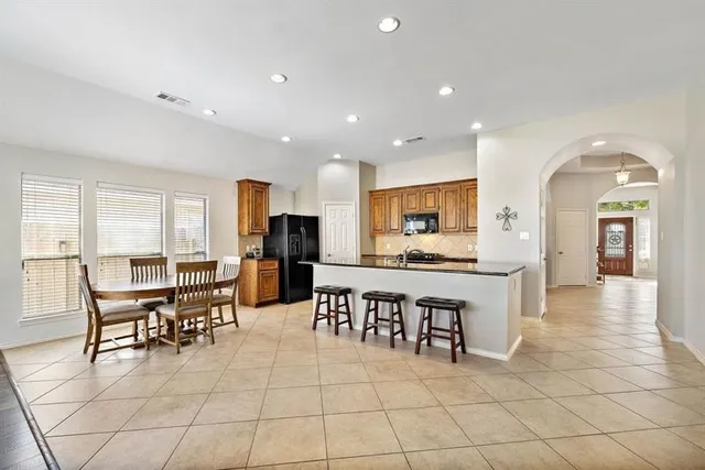 a open kitchen with stainless steel appliances kitchen island granite countertop a table and chairs in it