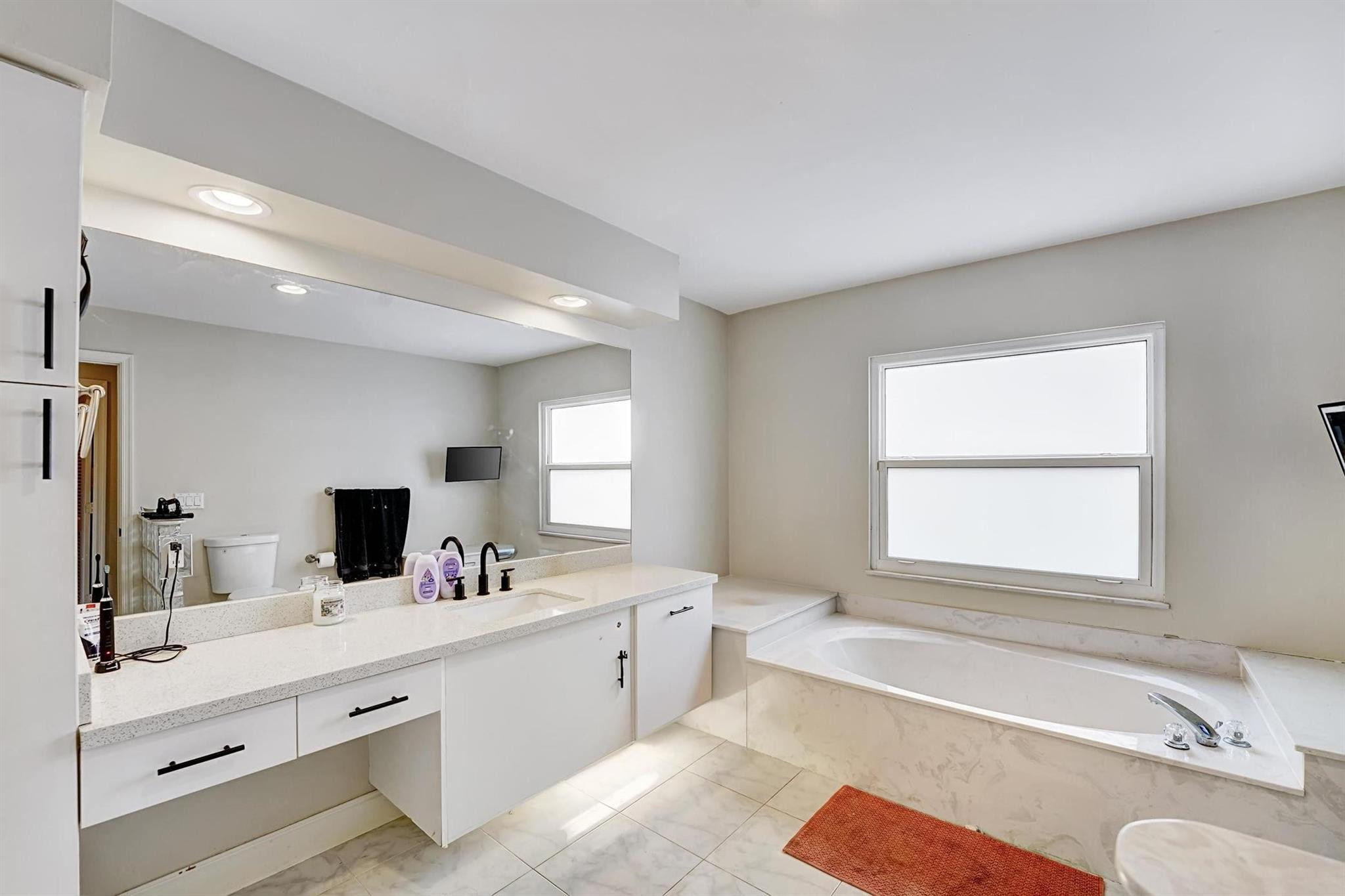 18219 Blue Lake Way Boca Raton, FL 33498 - Photo 22 of 39 a bathroom with a tub a double vanity sink a window a mirror and vanity