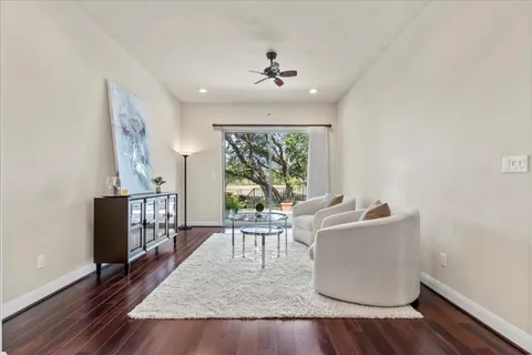 a living room with furniture large window and wooden floor