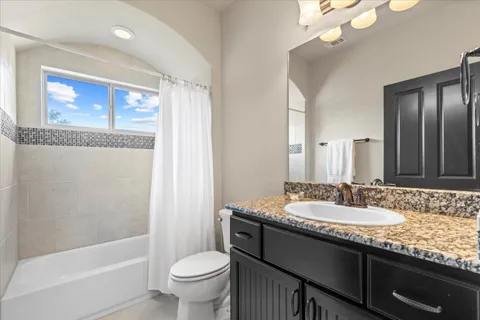 a bathroom with a granite countertop sink a toilet a mirror and shower