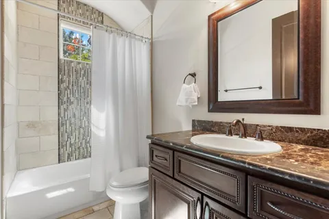 a bathroom with a granite countertop sink a toilet a mirror and shower