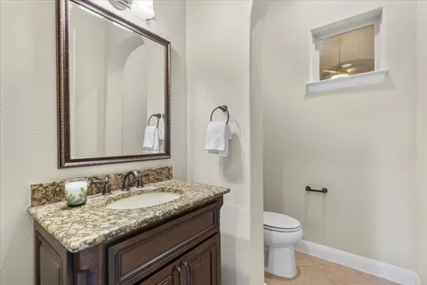 a bathroom with a granite countertop sink a toilet and a mirror