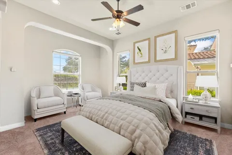 a bedroom with a bed couches chair and a window