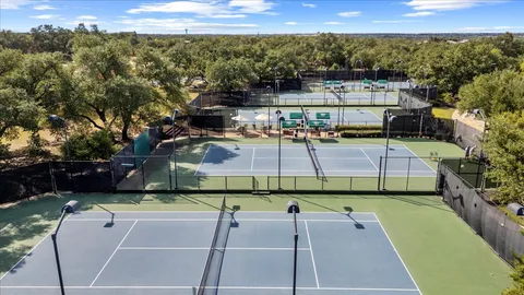 a view of a tennis ground with large trees