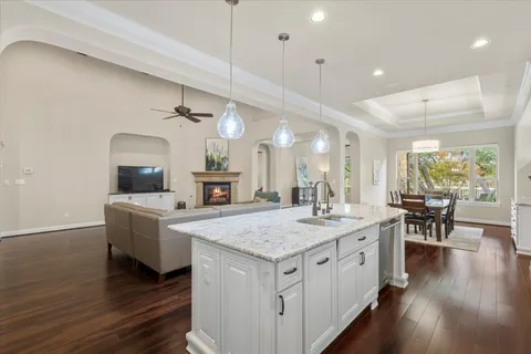 a hall with kitchen island a stove a wooden floors a dining table and chairs