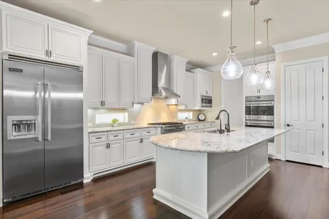 a kitchen with stainless steel appliances granite countertop a sink a refrigerator and a stove with wooden floor