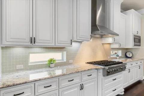 a kitchen with granite countertop stainless steel appliances white cabinets granite counter tops and a wooden floors