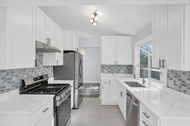 a kitchen with stainless steel appliances granite countertop a sink stove and refrigerator