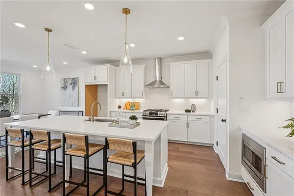 a kitchen with kitchen island granite countertop a dining table chairs wooden cabinets and white appliances