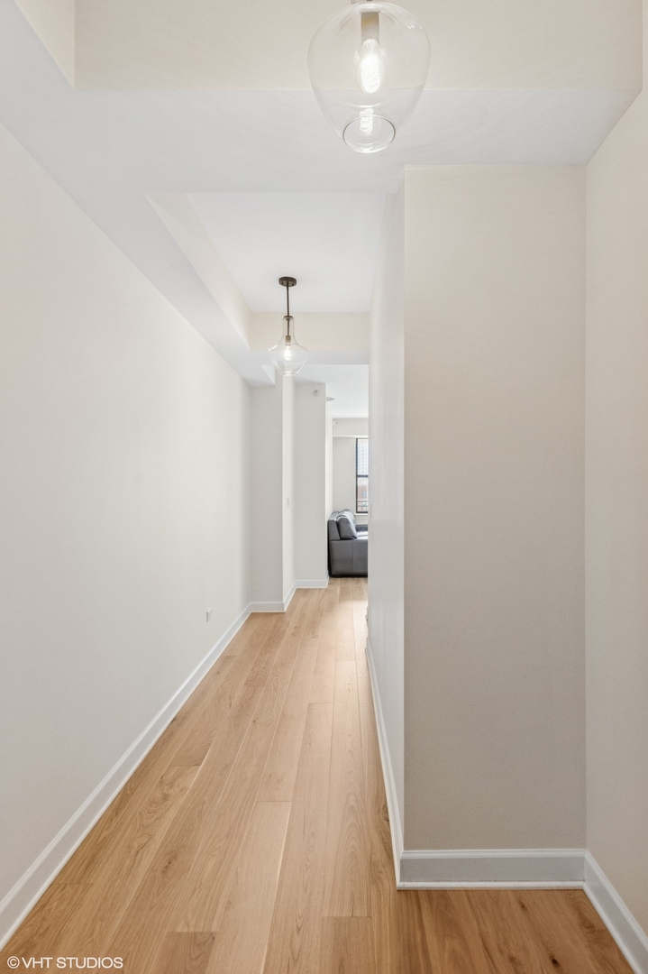 451 West Huron Street, Unit 910 Chicago, IL 60654 - Photo 24 of 27 a view of a hallway with wooden floor and a kitchen