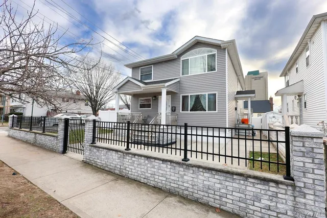a view of a white house with a small yard and large tree