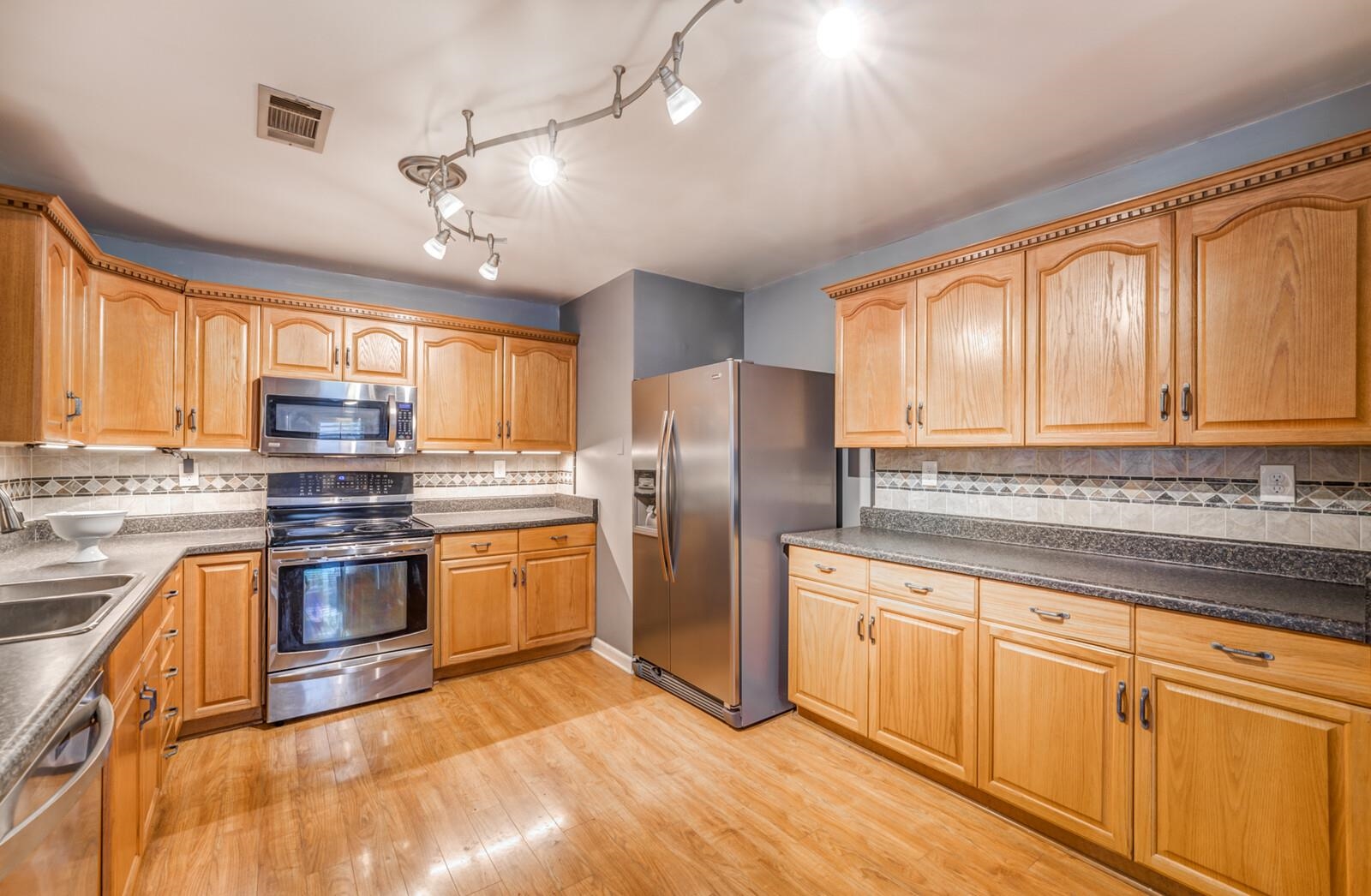 3089 Charles Bryan Road Bartlett, TN 38134 - Photo 8 of 28 a kitchen with stainless steel appliances granite countertop a refrigerator a sink dishwasher a stove and white cabinets with wooden floor