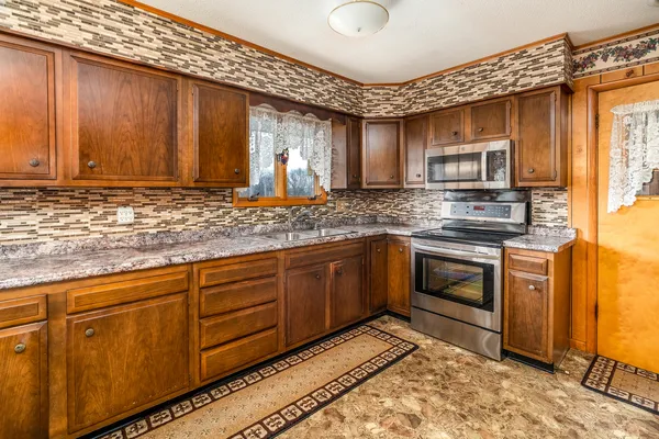 a kitchen with stainless steel appliances granite countertop a stove a sink and a microwave
