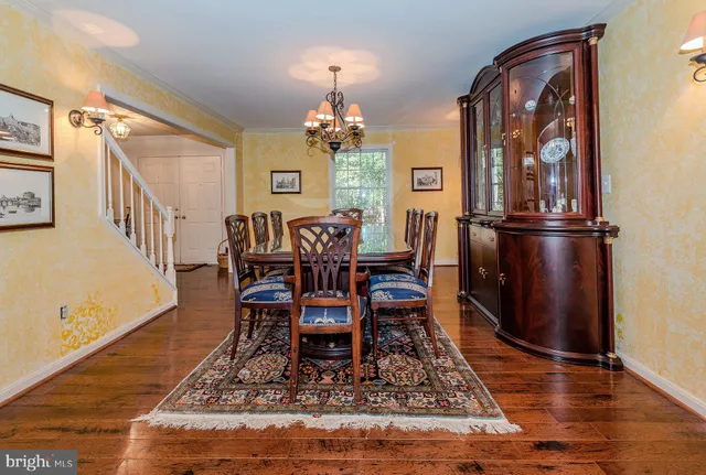 a dining room with wooden floor a chandelier a wooden table and chairs