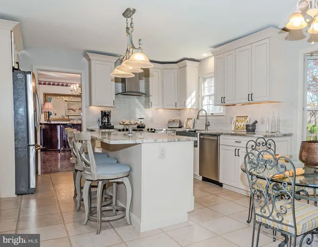 a kitchen with granite countertop a table chairs stove and refrigerator