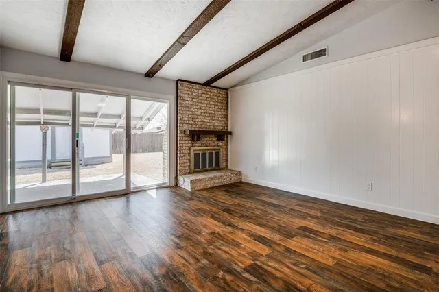 a view of empty room with wooden floor and fireplace