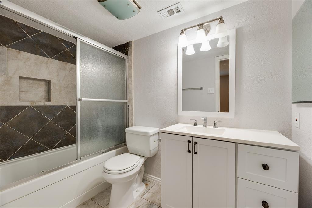 5109 Cedar Springs Road, Unit 105 Dallas, TX 75235 - Photo 13 of 16 Bathroom featuring a white vanity with a white countertop and rectangular sink, complemented by a mirror with a four-light fixture