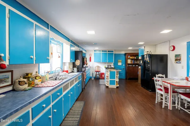 a kitchen that has a lot of cabinets a sink and wooden floor