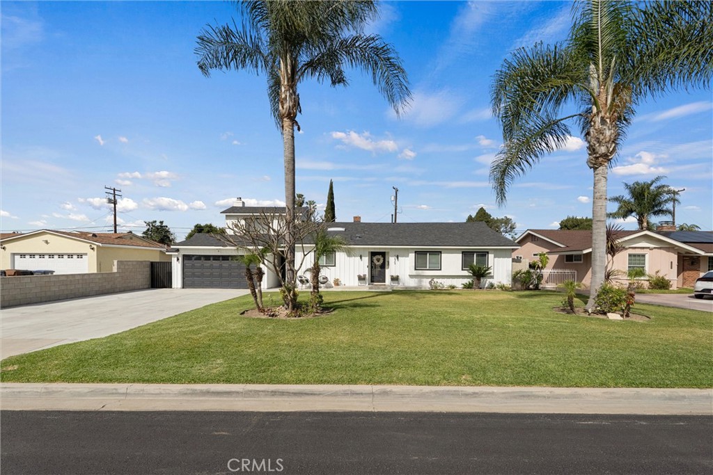 a view of a white house with a big yard and palm trees