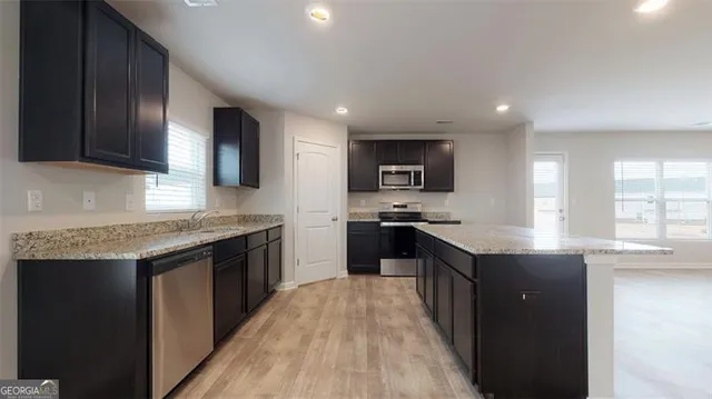 a kitchen with granite countertop kitchen island stainless steel appliances a sink stove top oven and cabinets