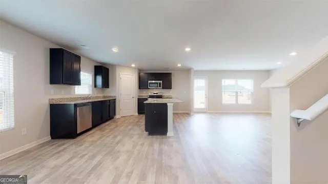 a large kitchen with stainless steel appliances kitchen island granite countertop a sink dishwasher a stove and a refrigerator with wooden floor