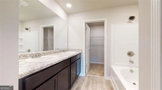 a bathroom with a granite countertop sink a mirror and a bathtub