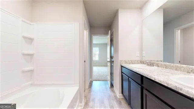 a bathroom with a granite countertop sink a mirror and a bathtub