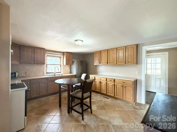a kitchen with stainless steel appliances granite countertop a sink a stove a table and chairs