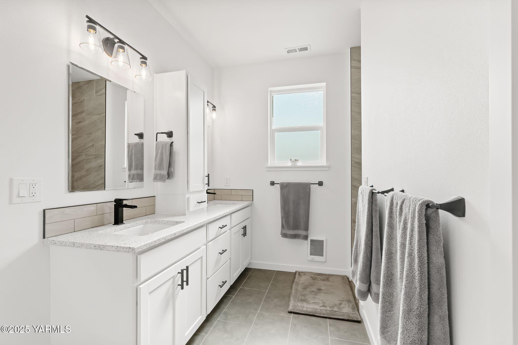 12907 Douglas Road Yakima, WA 98908 - Photo 17 of 44 a bathroom with a double vanity sink a mirror and a bathtub
